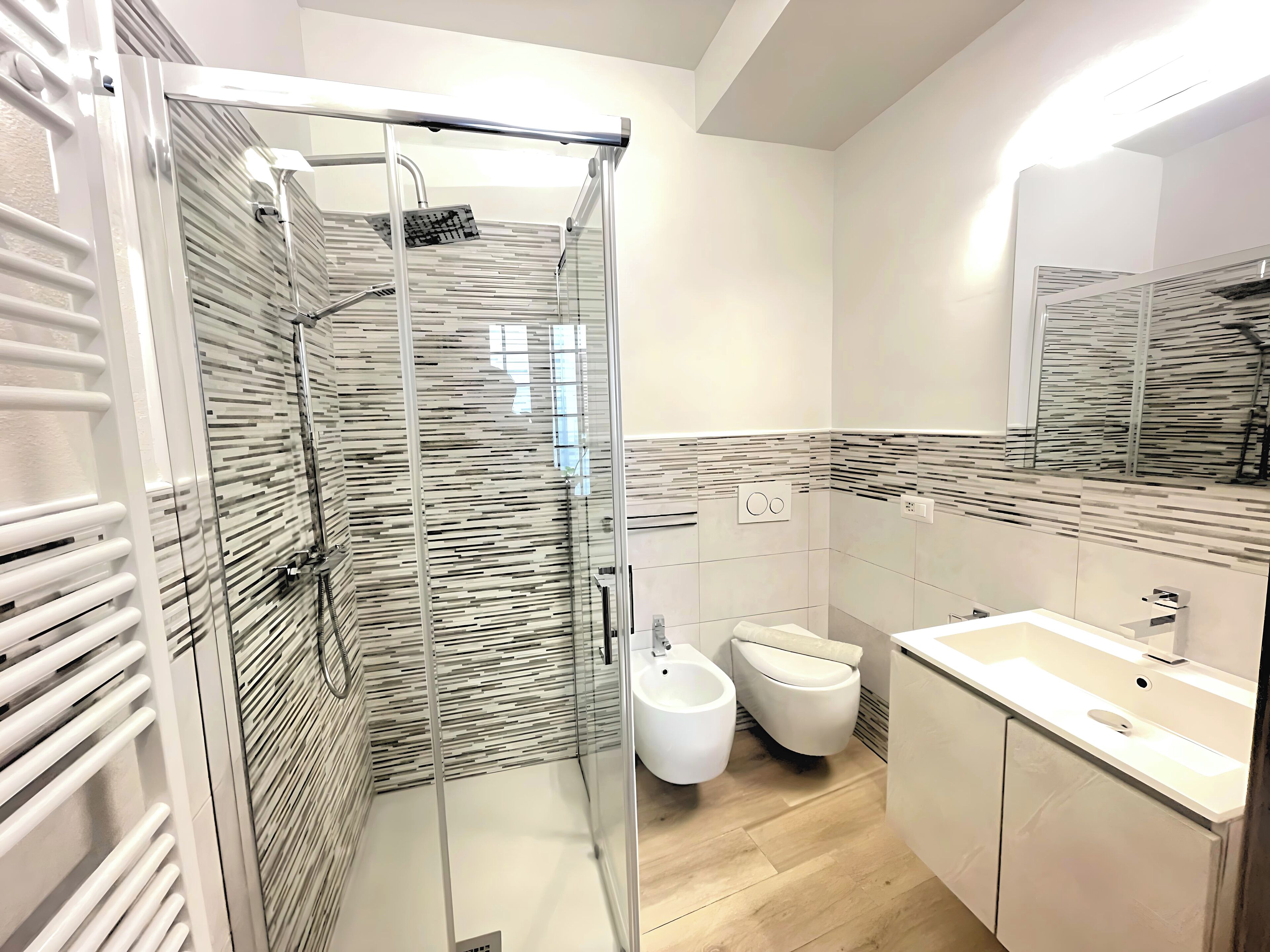A modern bathroom with a glass-enclosed shower, a bidet, and a sink.
