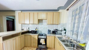 A compact kitchen with wooden cabinets, a microwave, a stove, and a sink.