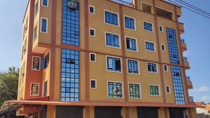 A multi-story building with a yellow facade, multiple windows, and a sign indicating it is an executive bedroom building.