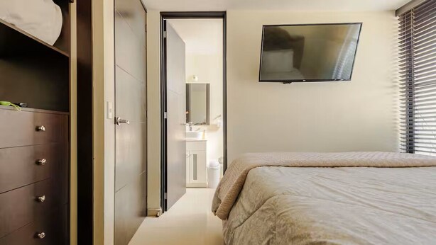 Une chambre à coucher avec un lit, un téléviseur fixé au mur et une armoire.