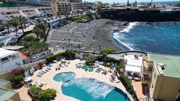 A resort with a large pool, beach access, and a view of the ocean.