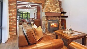 Ein gemütliches Wohnzimmer mit Kamin aus Backstein, einer Ledersofa und einem Holztisch.