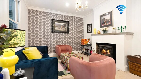 A living room with a fireplace, patterned wallpaper, and a blue sofa.