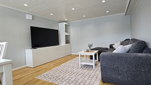 A modern living room with a flat-screen TV, grey sofa, white furniture, and a patterned rug. - Newly renovated apartment in Skärhamn within walking distance to the beach | SE09138 (Skärhamn)