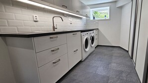 A laundry room with a washing machine, a sink, and a window with a view of greenery. - Newly renovated apartment in Skärhamn within walking distance to the beach | SE09138 (Skärhamn)