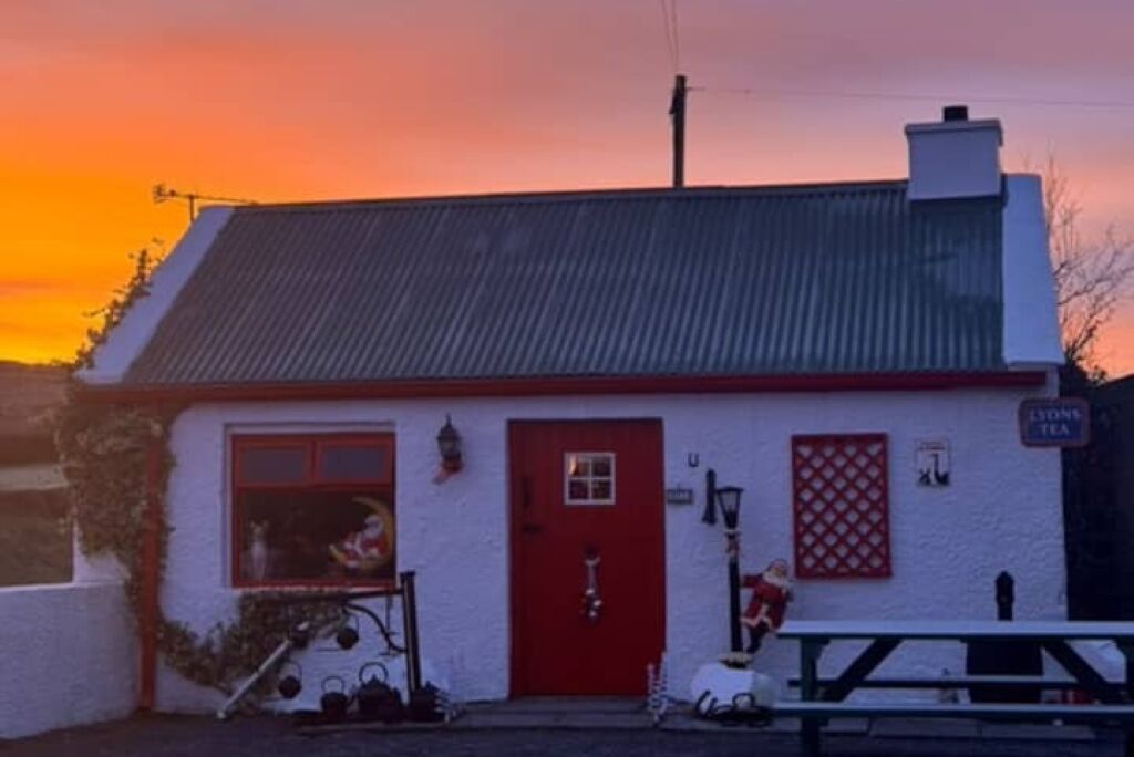 A white building with a red door and a sign that reads "Lions Tea".
