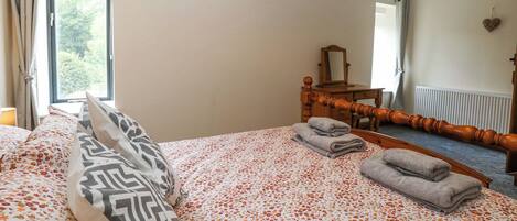 A bedroom with a bed, a dresser, a mirror, and a window with curtains.
