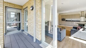Un appartement moderne doté d’un balcon, de portes-fenêtres coulissantes, d’une cuisine et d’un coin salon.