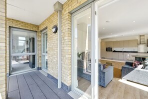 Un apartamento moderno con balcón, puertas correderas de vidrio, cocina y zona de estar.