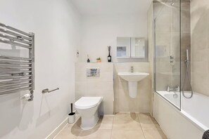 Une salle de bain moderne avec une douche à parois de verre, un lavabo blanc et des toilettes.