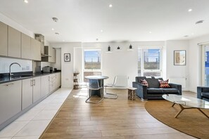 A modern kitchen with a dining area, a sofa, and a glass table.