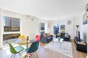 Ein modernes Wohnzimmer mit einer Couch, Sesseln, einem Couchtisch und einem Fernseher.