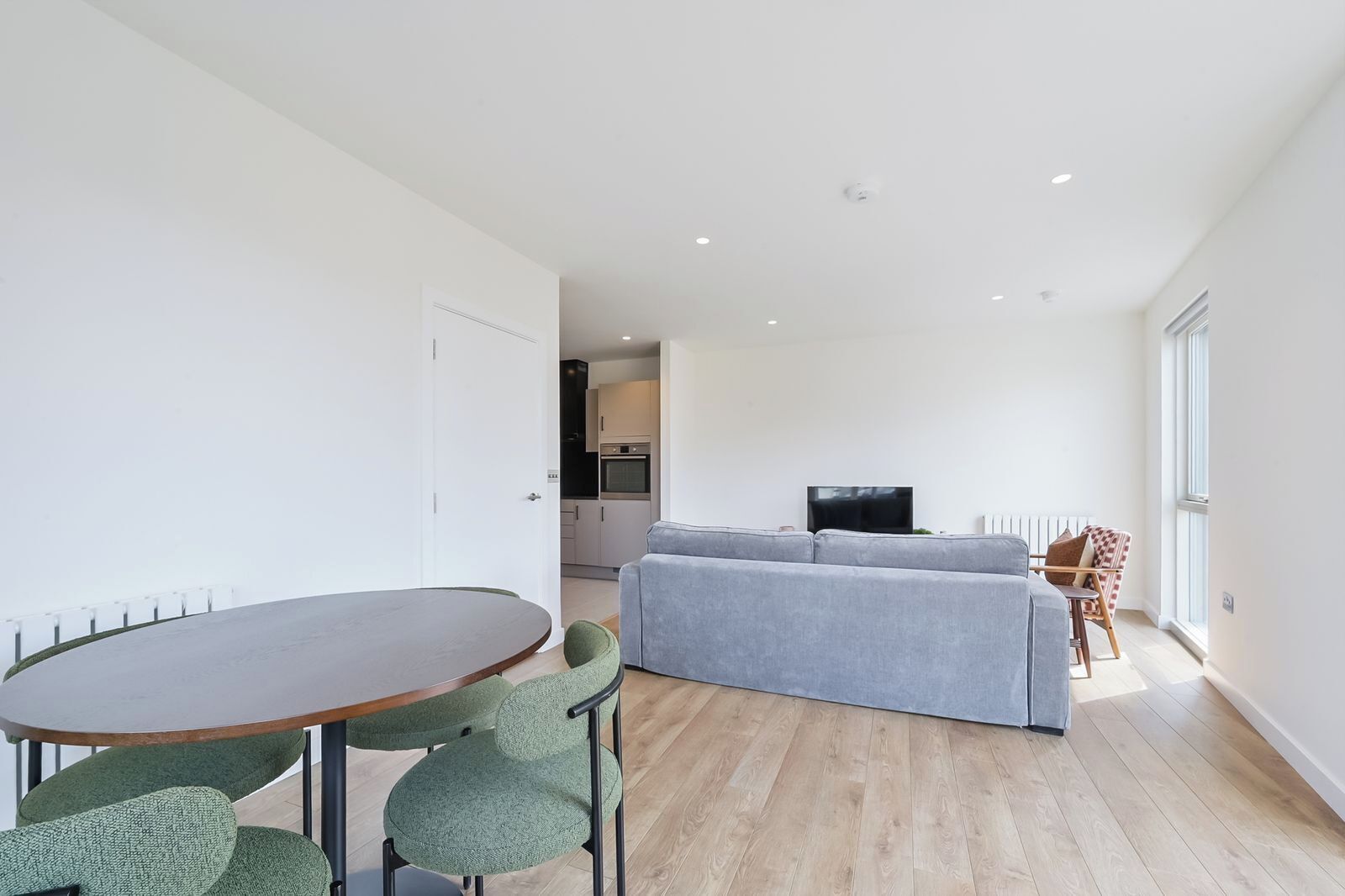 A modern living space with a dining area, a sofa, and a television.