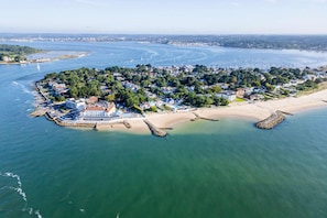 Vue aérienne d’une ville côtière avec un port de plaisance, une plage et un quartier résidentiel.