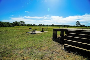 A grassy field with a wooden bench and a picnic table.