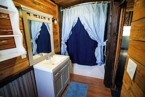 A bathroom with wooden walls, a white sink, and a dark blue shower curtain.