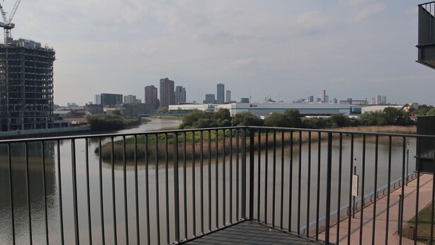 Un balcón con vistas a un río, un puente y el horizonte de una ciudad con edificios altos.