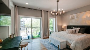 A bedroom with a large bed, a desk, and a view of a balcony. - Luxury 10-Bed Home w/ HUGE Rooftop & Game Room! (Nashville)