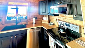 A wooden cabin interior with a kitchen featuring a stove, microwave, and wooden cabinets. - Pigeon forge Views Hot Tub Private Gatlinburg (Carolina)