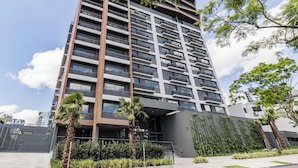 Een modern hoog gebouw met meerdere balkons, een hekpoort en omliggend groen.