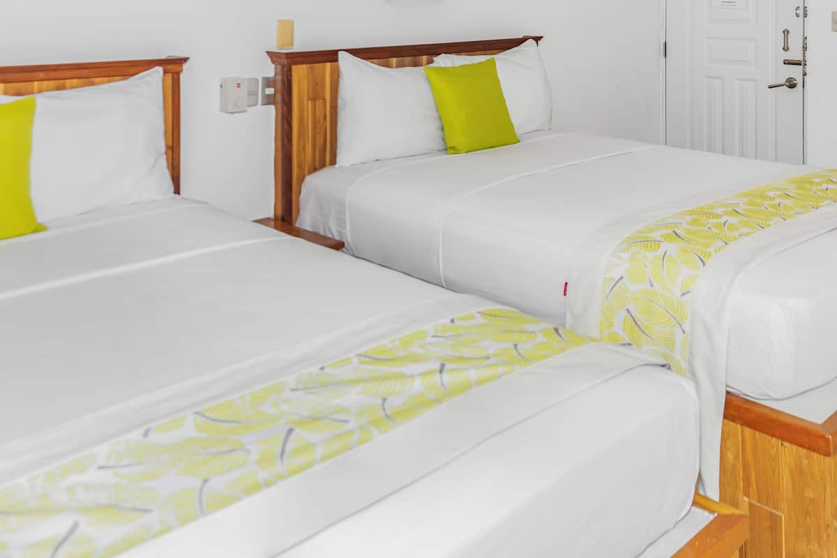 Two single beds with wooden headboards and white bedding, one with a yellow pillow.