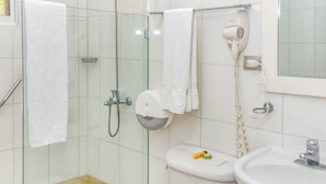 A bathroom with a glass shower enclosure, a toilet, a sink, and a hairdryer mounted on the wall. - Hotel & Restaurant Chino (Samaná)