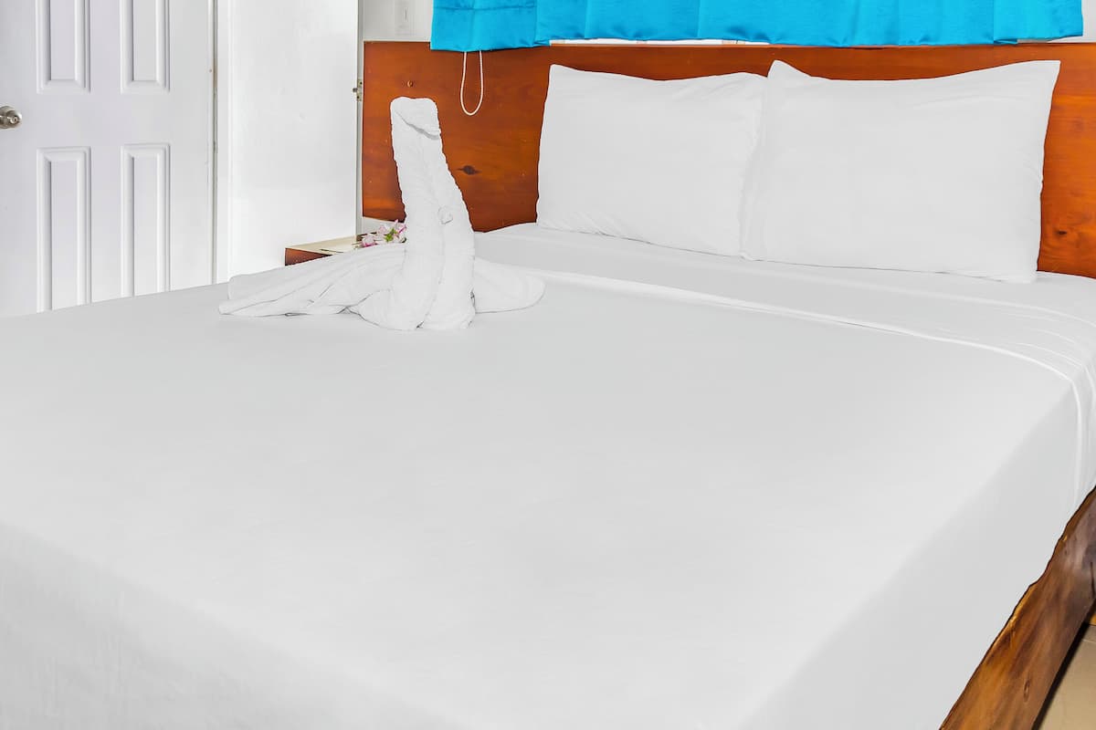 A neatly made bed with white linens and a wooden headboard.