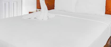 A neatly made bed with white linens and a wooden headboard.