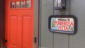 Een rode deur met een welkomstbord voor Ponderosa Vista.