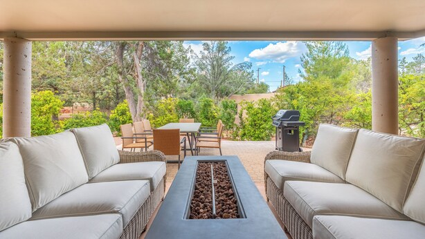 Un espace extérieur aménagé avec un canapé, des chaises, une table et un barbecue.