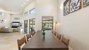 Un grand espace dédié à la salle à manger, avec une longue table en bois, entourée de chaises, et une plante en pot placée au centre.