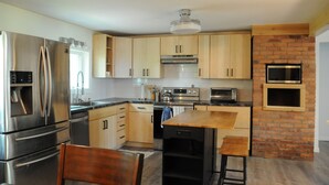Una cocina moderna con electrodomésticos de acero inoxidable, armarios de madera y una pared decorativa de ladrillo.