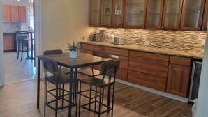 A kitchen with wooden cabinets, a granite countertop, and a dining area with a table and chairs.