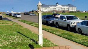 A parking lot with cars, a white lamp post, and a building with an American flag in the background.
