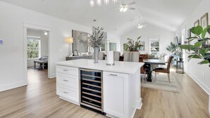 Une cuisine spacieuse dotée d’un îlot central, de luminaires suspendus modernes et d’un ventilateur de plafond.