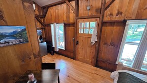 A wooden interior with a kitchen area, a dining table, and a bed. - Lazy T Cabins - Glacier (Graham County)