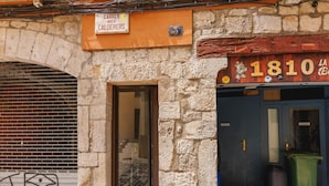 Un bâtiment en pierre avec une fenêtre fermée par un volet, une porte et une enseigne indiquant « Carrer dels Calderers ».