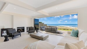 Ein modernes Wohnzimmer mit einem großen Fenster mit Blick auf einen Strand.