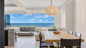 Ein stilvoller Wohnbereich mit großem Esstisch, einer Couch und Blick auf den Strand.