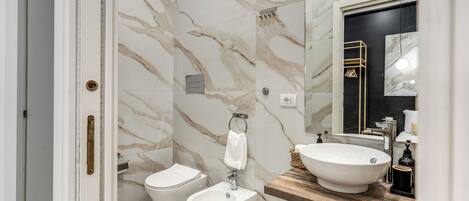 A bathroom with a bidet, a sink, and a mirror.