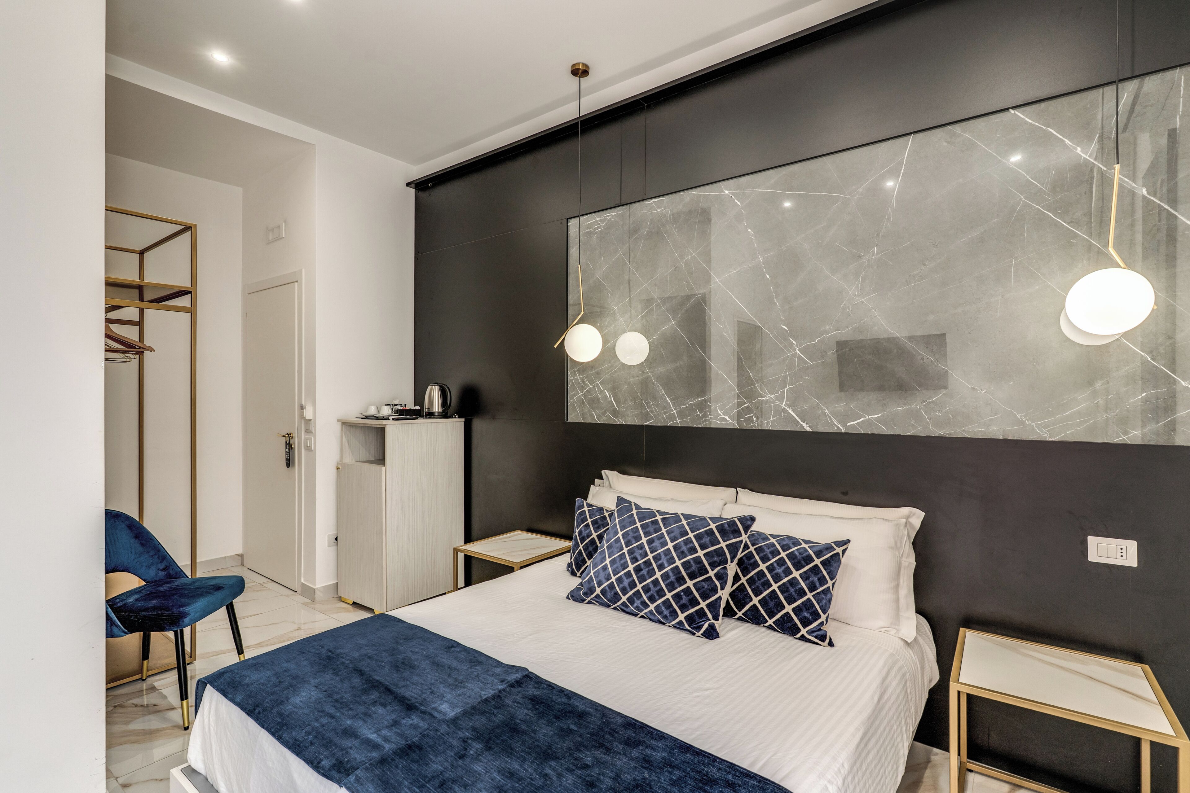A modern bedroom with a large bed, bedside tables, a wardrobe, and a mirror with a marble-like design.
