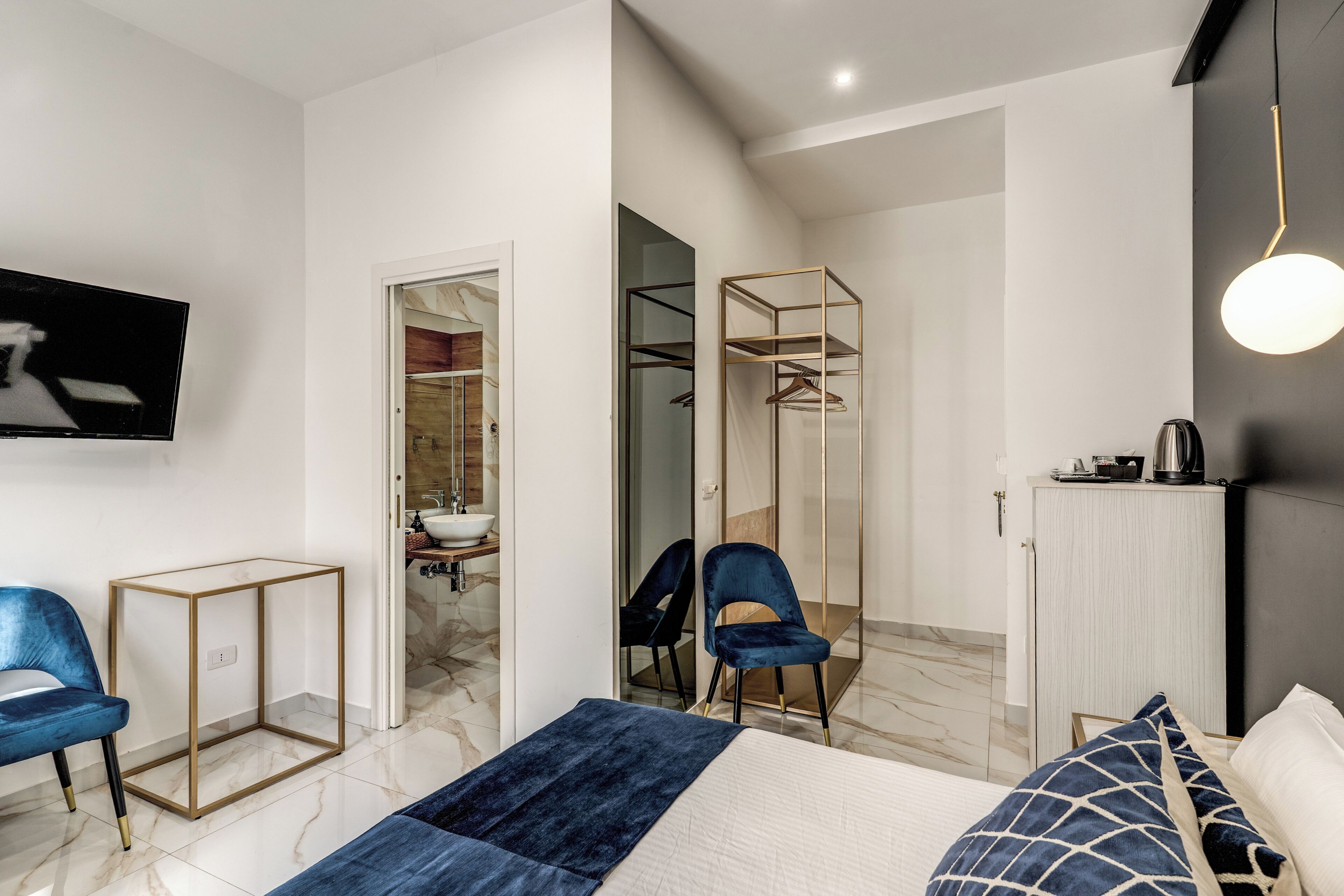 A modern bedroom with a bed, a TV, a wardrobe, and a mirror.