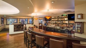 A bar area with a curved counter, bar stools, and a city view through large windows. - Marines Memorial Club & Hotel  (San Francisco)