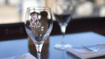 Two empty wine glasses on a table with a city view in the background.