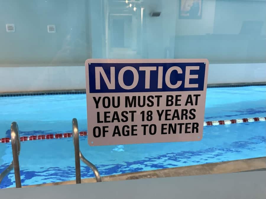 A pool area with a sign stating age restriction.