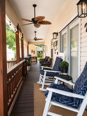 Ein überdachter Balkon mit Holzbalkonen, Deckenventilatoren und Sitzgelegenheiten mit gemusterten Kissen.