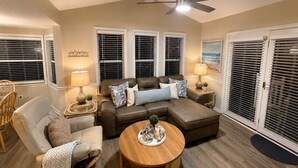 A living room with a brown leather sofa, two side chairs, a wooden coffee table, and a ceiling fan.