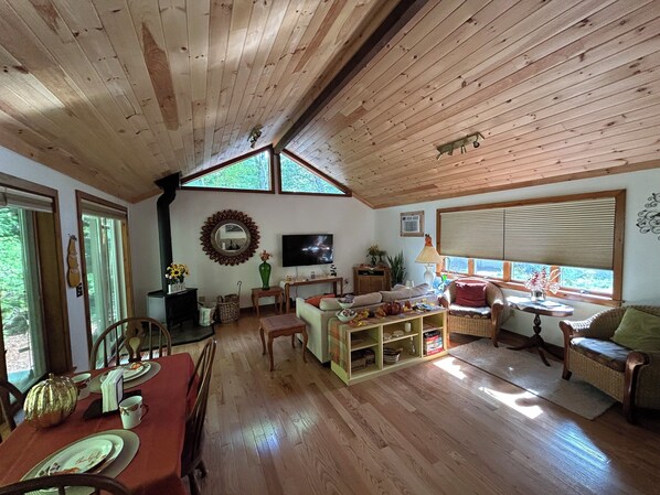 Un intérieur de chalet chaleureux comprenant un coin repas, un salon et de grandes fenêtres.