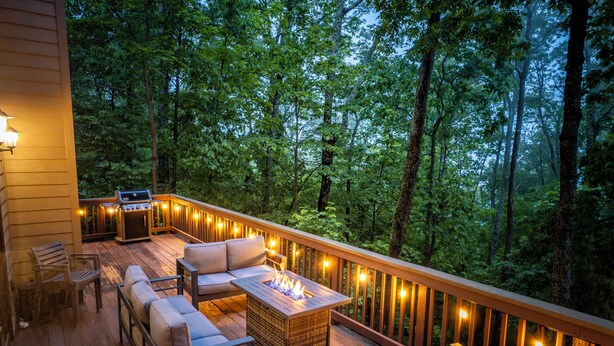 Een terras met tuinmeubilair, een vuurkorf en lichtjes.