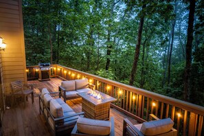 Eine Terrasse mit Gartenmöbeln, einem Feuerkorb und Lichterketten.